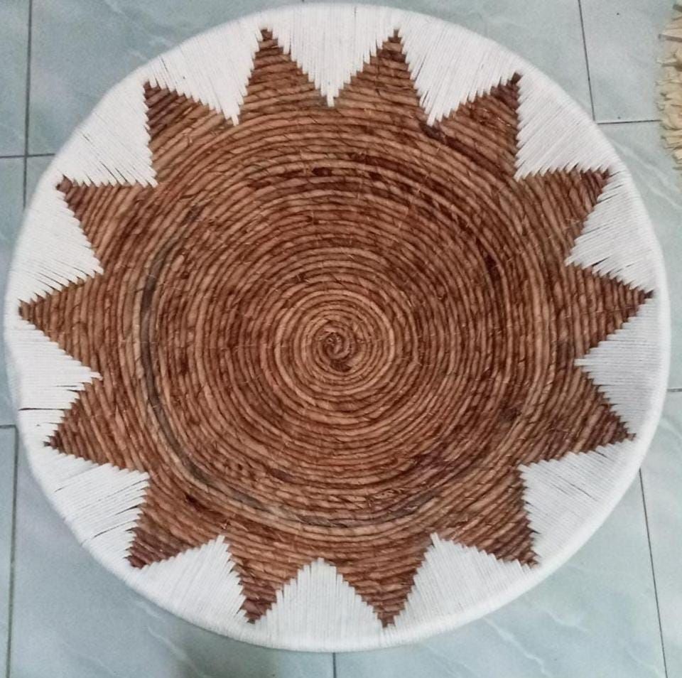 Top view of a circular woven basket with a jagged star pattern in brown and white.